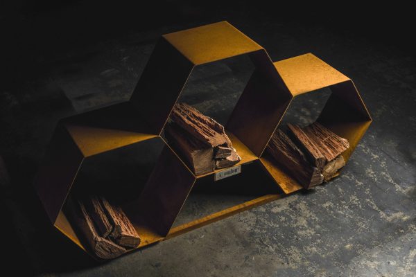 A firewood storage rack, shaped like honeycomb in a rusty corten steel finish.