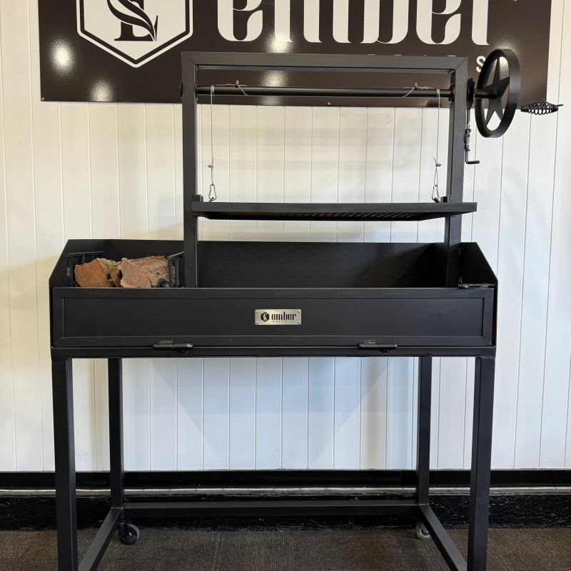 An Australian made Parilla Grill by Ember Industries. A wind up grill welded onto a black metal trolley, with a side brazier for burning timber.